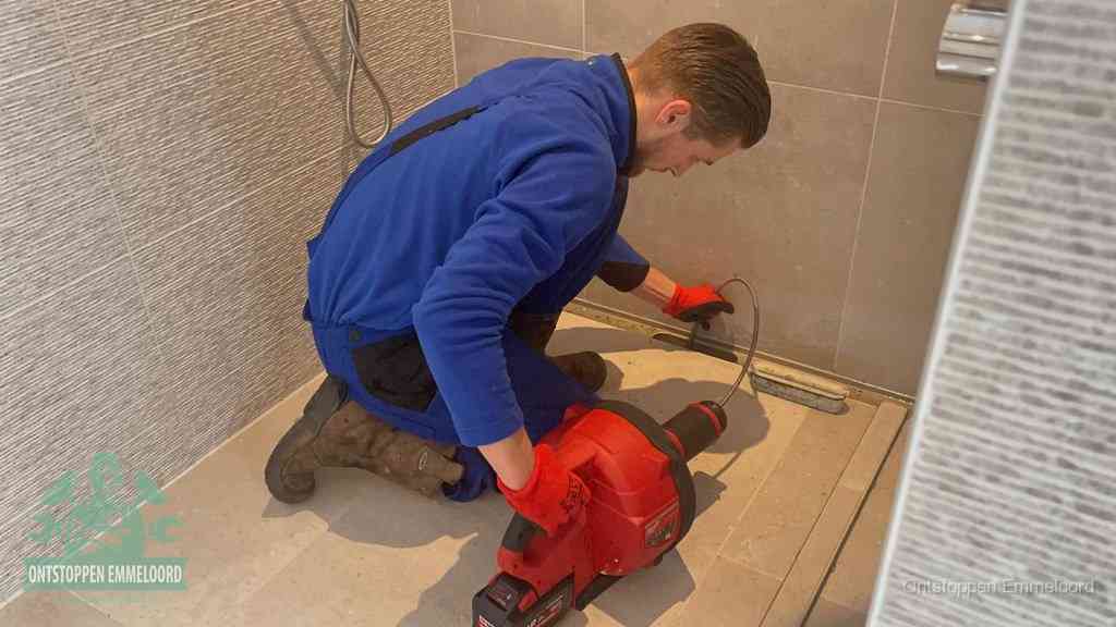 Een monteur ontstopt een langwerpige douchegoot met een elektrische veer, een doucheputje verstopt door haren en zeep in Emmeloord