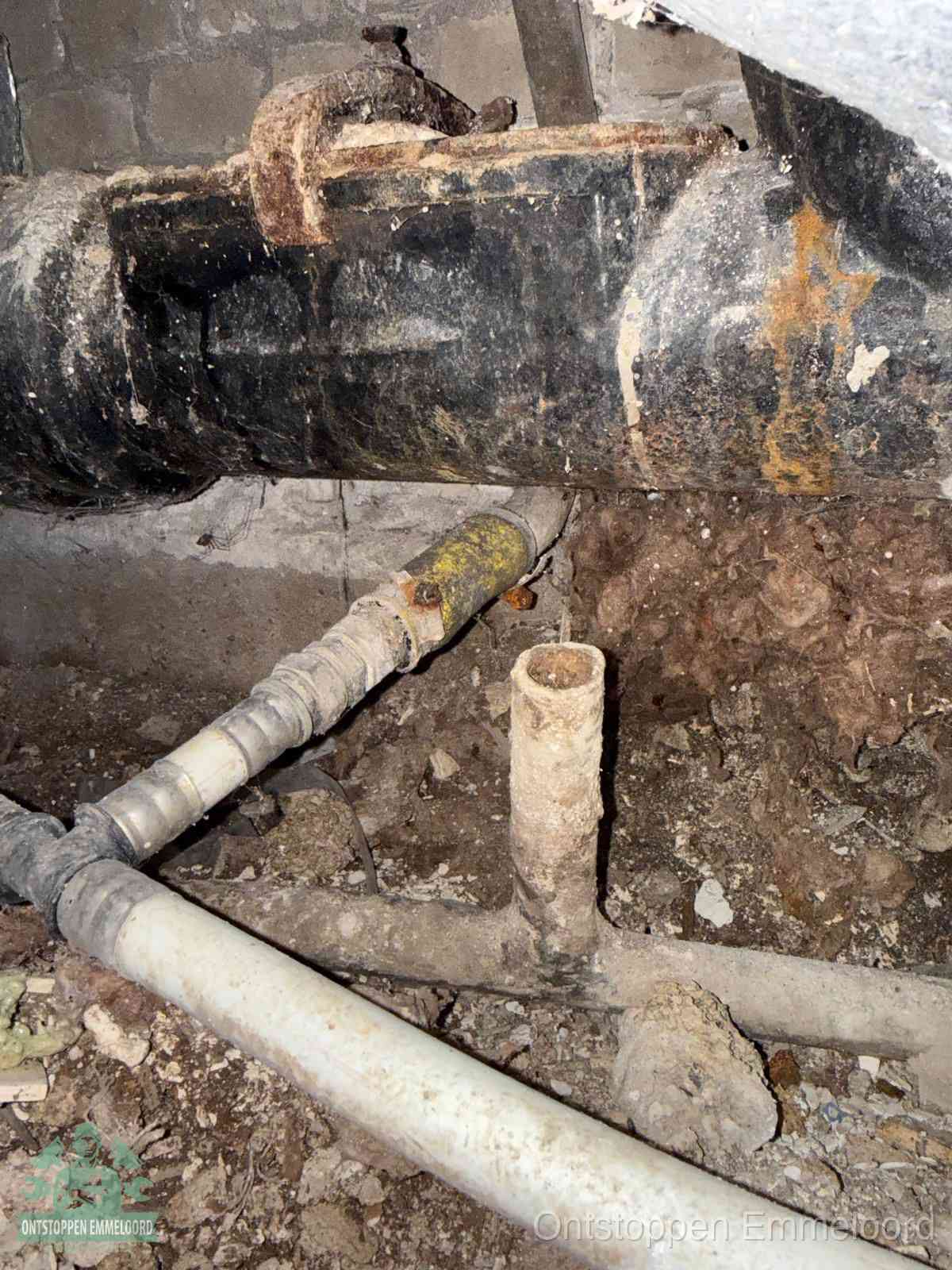 Een oude hoofdrioolbuis met roest- en kalkaanslag in een kruipruimte, oorzaak van terugkerende structurele rioolproblemen in Emmeloord